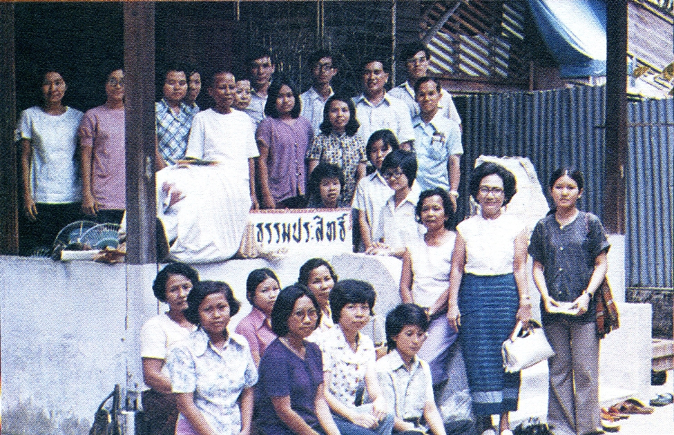 อุบาสิกาจันทร์ ขนนกยูง (แม่ชีจันทร์) ผู้สอนวิชาธรรมกายให้พระธัมมชโย ถ่ายภาพร่วมกับหมู่คณะรุ่นแรกที่บ้านธรรมประสิทธิ์ วัดปากน้ำ ภาษีเจริญ