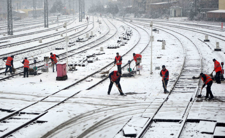 Workers remove snow from railways at a train station in Nanchang