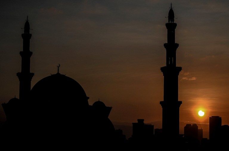A general view shows a partial solar eclipse behind the Wilayah mosque in Kuala Lumpur on March 9, 2016. A total solar eclipse swept across the vast Indonesian archipelago on March 9, witnessed by tens of thousands of sky gazers and marked by parties, Muslim prayers and tribal rituals. Partial eclipses were also visible over other parts of Asia and Australia. / AFP / MANAN VATSYAYANA