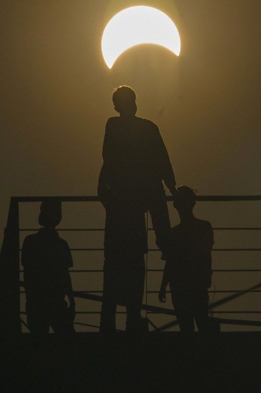 Acehnese men watch the total solar eclipse in Banda Aceh on March 9, 2016. A total solar eclipse swept across the vast Indonesian archipelago on March 9, witnessed by tens of thousands of sky gazers and marked by parties, Muslim prayers and tribal rituals. / AFP / CHAIDEER MAHYUDDIN