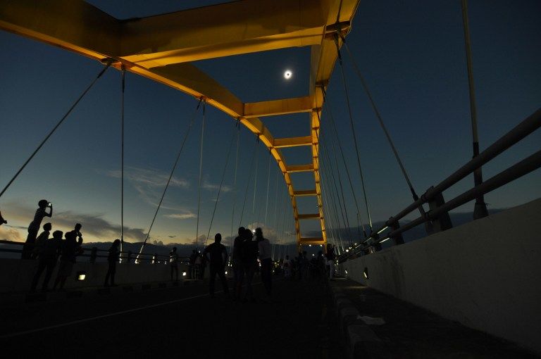 People watch a total total solar eclipse in Palu, Central Sulawesi on March 9, 2016. A total solar eclipse swept across the vast Indonesian archipelago on March 9, witnessed by tens of thousands of sky gazers and marked by parties, Muslim prayers and tribal rituals. / AFP / NANANG