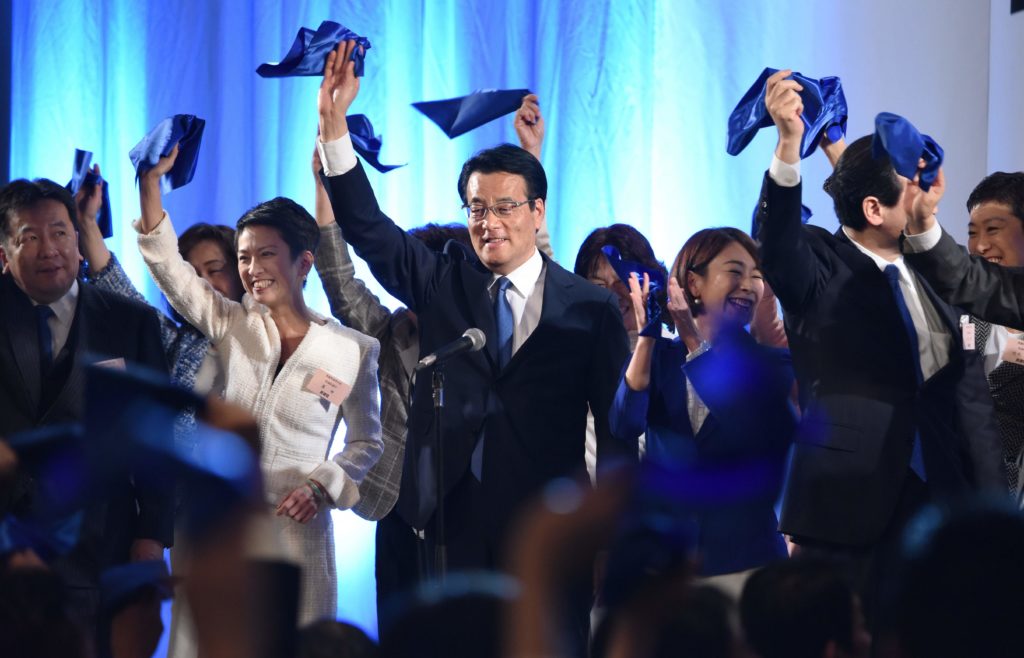 นายคัตสึยะ โอกาดะ พร้อมสมาชิกพรรคประชาธิปไตย พรรคการเมืองใหม่ของญี่ปุ่น โบกผ้าเช็ดมือสีน้ำเงิน ระหว่างพิธีเปิดตัวพรรคใหม่ ที่กรุงโตเกียว ประเทศญี่ปุ่น เมื่อวันที่ 27 มีนาคม (ภาพ AFP)