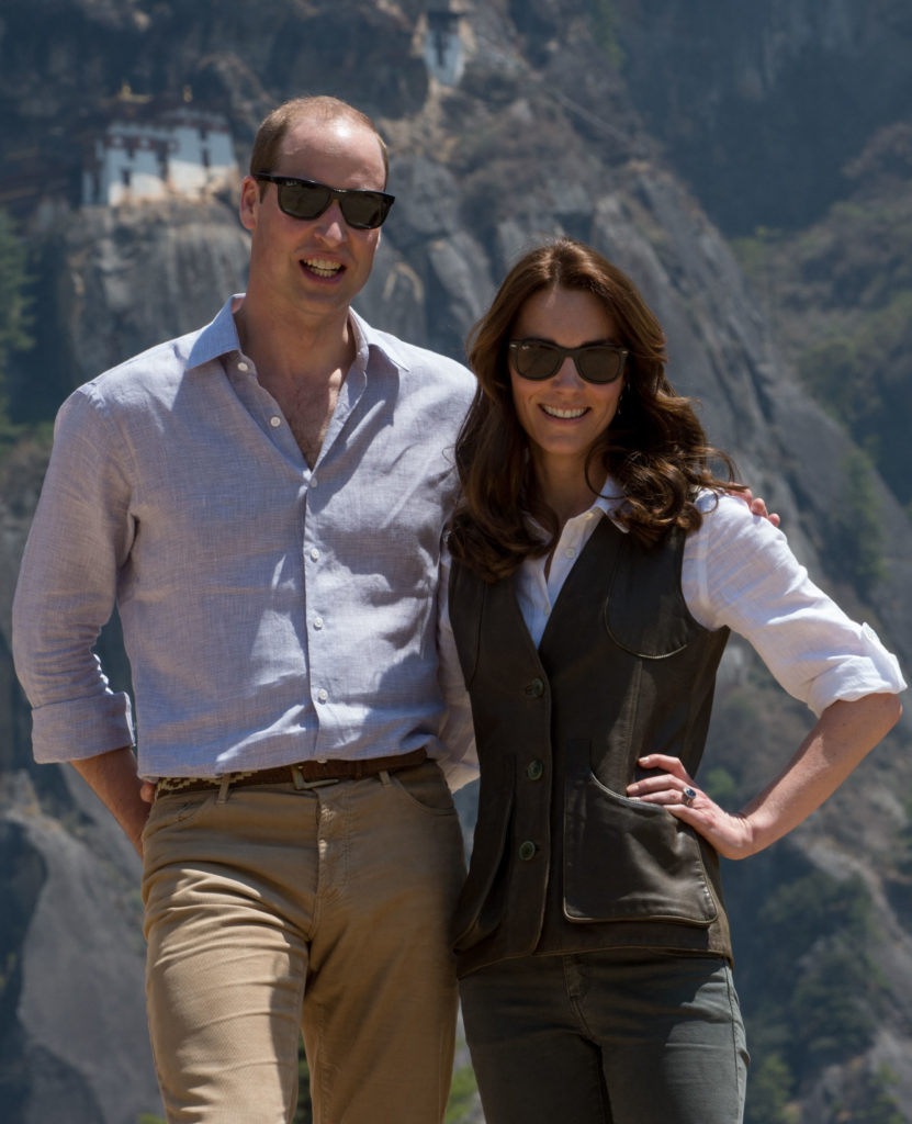 Britain's Prince William (L), Duke of Cambridge, and Catherine, Duchess of Cambridge, pose for a photograph halfway up the trail leading to a Buddhist monastery referred to as the "Tiger's Nest" (behind) on their two-day visit to Bhutan on April 15, 2016. / AFP PHOTO / ROBERTO SCHMIDT