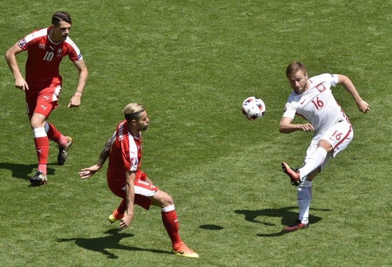 Poland's midfielder Jakub Blaszczykowski (R) attempts a shot as he is marked by Switzerland's midfielder Valon Behrami (C) and Switzerland's midfielder Granit Xhaka during the Euro 2016 round of sixteen football match Switzerland vs Poland, on June 25, 2016 at the Geoffroy Guichard stadium in Saint-Etienne. / AFP PHOTO / JEAN-PHILIPPE KSIAZEK