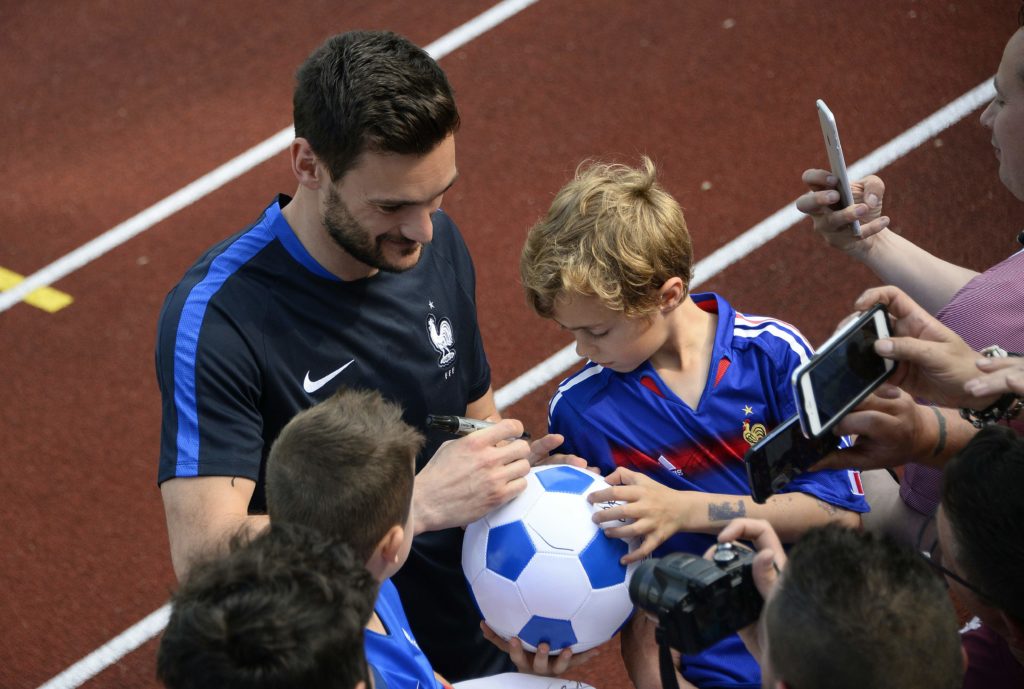 France's goalkeeper Hugo Lloris (L) signs an autograph before a training session at France's training ground in Clairefontaine-en-Yvelines, southwest of Paris, on June 6, 2016, ahead of the beginning of the Euro 2016 football tournament. / AFP PHOTO / FRANCK FIFE