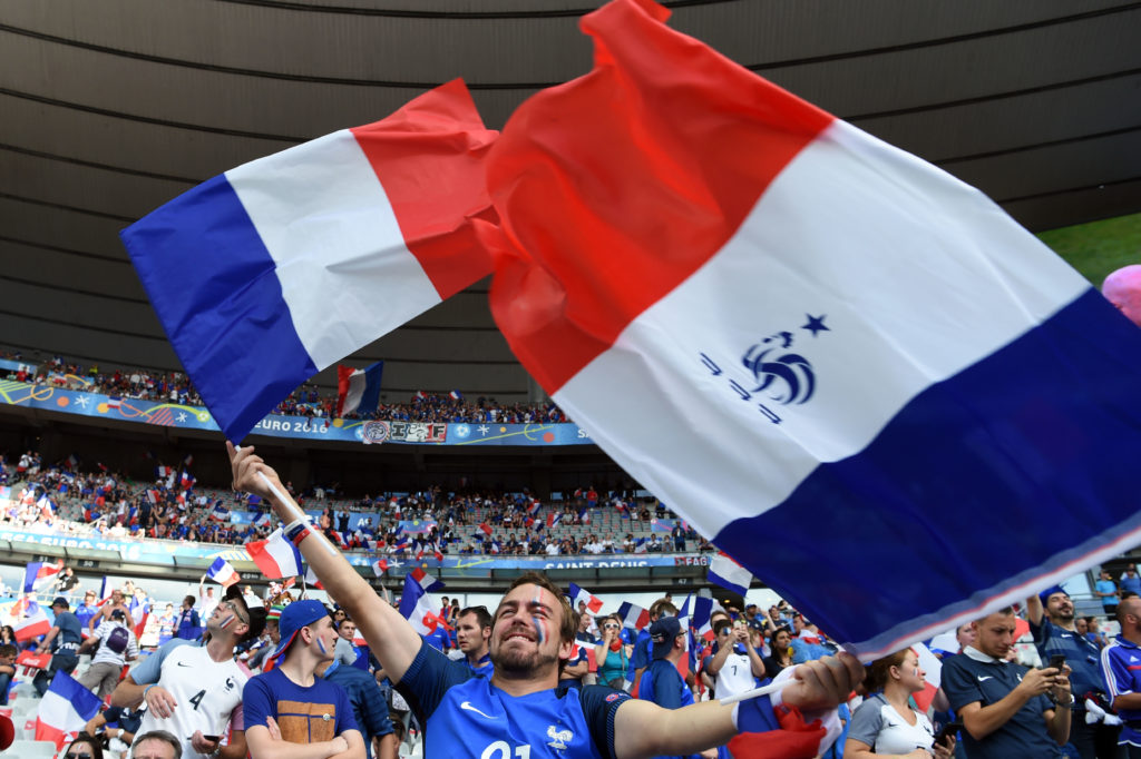 French supporters wave French national flags as they cheer ahead of the Euro 2016 final football match between Portugal and France at the Stade de France in Saint-Denis, north of Paris, on July 10, 2016. / AFP PHOTO / PATRIK STOLLARZ