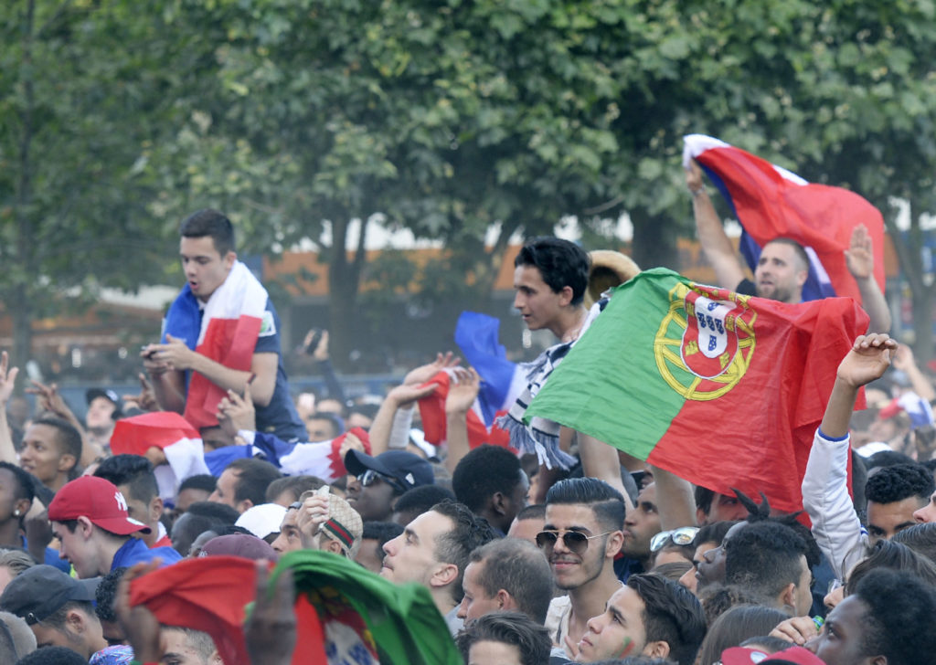 France and Portugal supporters cheer prior to the Euro 2016 final football match between Portugal and France at the Champ-de-Mars fan zone in Paris on July 10, 2016. With each France match, the 90,000 capacity fan zone at the foot of the Eiffel Tower has been progressively fuller. / AFP PHOTO / ALAIN JOCARD