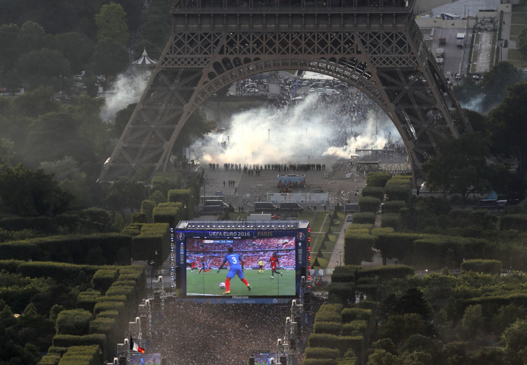 A picture taken from the Tour Montparnasse shows tear gas under the Eiffel tower during clashes between police and supporters trying to illegally enter the Champs de Mars fan zone on July 10, 2016 in Paris, before the Euro 2016 football tournament final match between Portugal and France. / AFP PHOTO / Thomas SAMSON