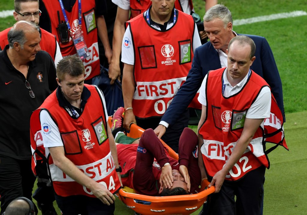 France's coach Didier Deschamps (2R) walks next to Portugal's forward Cristiano Ronaldo (C) who is carried on a stretcher off the pitch by medics after an injury following a clash with France's forward Dimitri Payet (not pictured) during the Euro 2016 final football match between Portugal and France at the Stade de France in Saint-Denis, north of Paris, on July 10, 2016. / AFP PHOTO / MIGUEL MEDINA