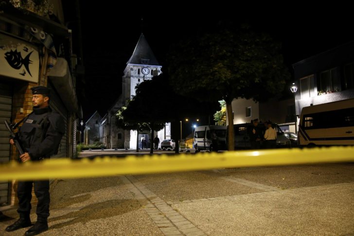 French police stand guard near the church in Saint-Etienne-du-Rouvray, France, where French priest, Father Jacques Hamel, was killed with a knife and another hostage seriously wounded in an attack on the church