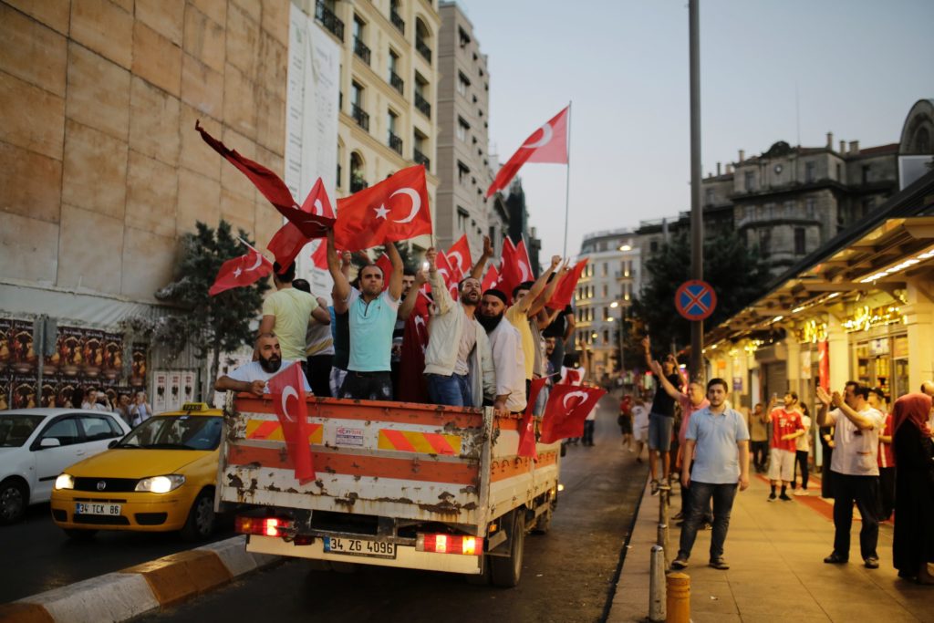 People in a truck wave Turkish flags in Istanbul on July 16, 2016 near Taksim square during a demonstration in support to Turkish president. President Recep Tayyip Erdogan battled to regain control over Turkey on July 16, 2016 after a coup that claimed more than 250 lives, bid by discontented soldiers, as signs grew that the most serious challenge to his 13 years of dominant rule was faltering. / AFP PHOTO / YASIN AKGUL