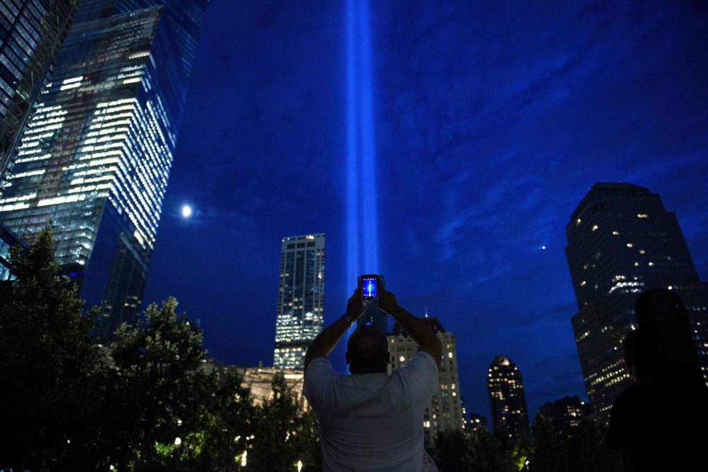 A man photographs beams of light symbolizing the two World Trade Center towers the night before the 15th anniversary of the September 11, 2001 terrorist attacks in the United States on September 10, 2016 in New York, New York. / AFP PHOTO / Brendan Smialowski