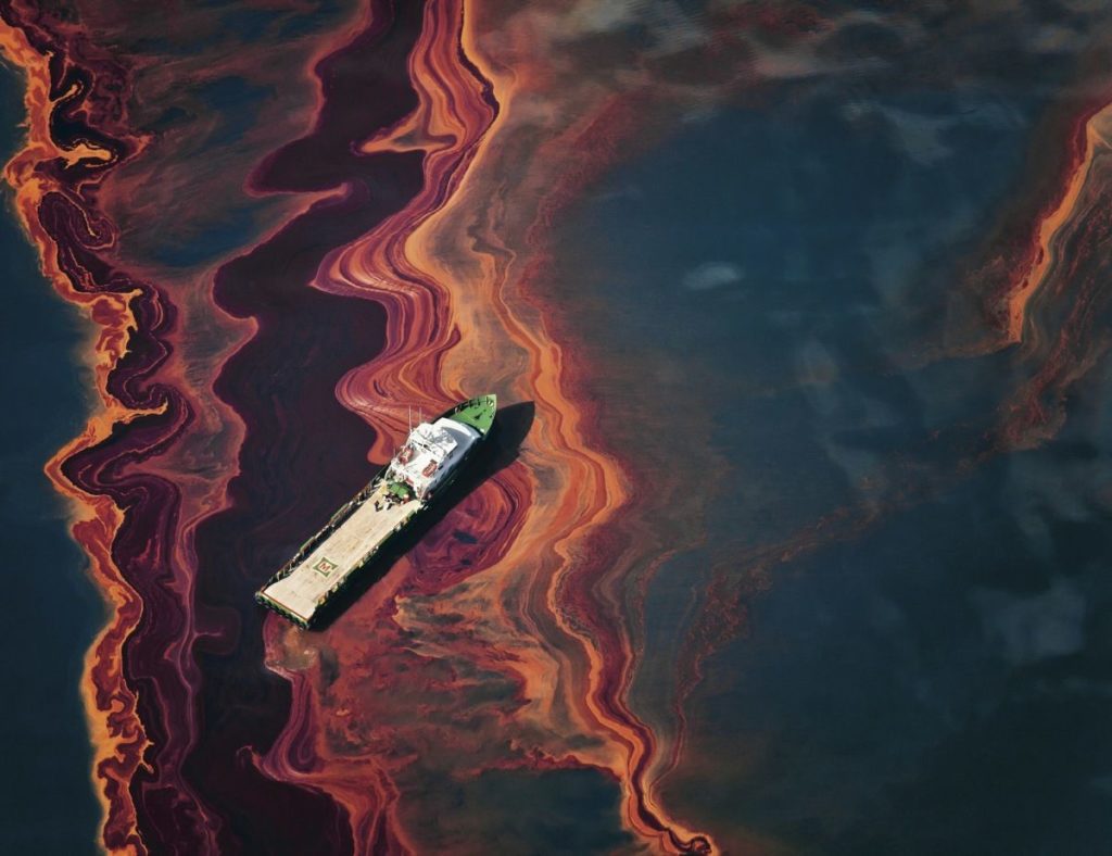 On May 6, 2010, a ship cuts through a band of oil on the surface of the Gulf of Mexico that seeped up from the Deepwater Horizon wellhead.  Photo ? Daniel Beltra for Greenpeace.