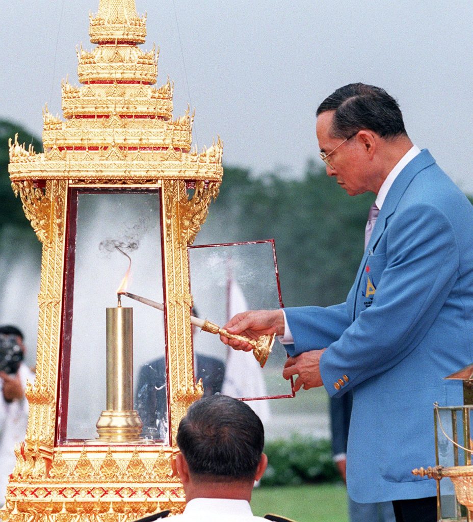 (FILES) This file photo taken on December 3, 1998 shows Thai King Bhumibol Adulyadej lighting the flame of the 13th Asian Games at Chitrlada Palace in Bangkok during a ceremony prior to the start of the games. Thailand's King Bhumibol Adulyadej has died after a long illness, the palace announced on October 13, 2016, ending a remarkable seven-decade reign and leaving a divided people bereft of a towering and rare figure of unity. / AFP PHOTO / PORNCHAI KITTIWONGSAKUL