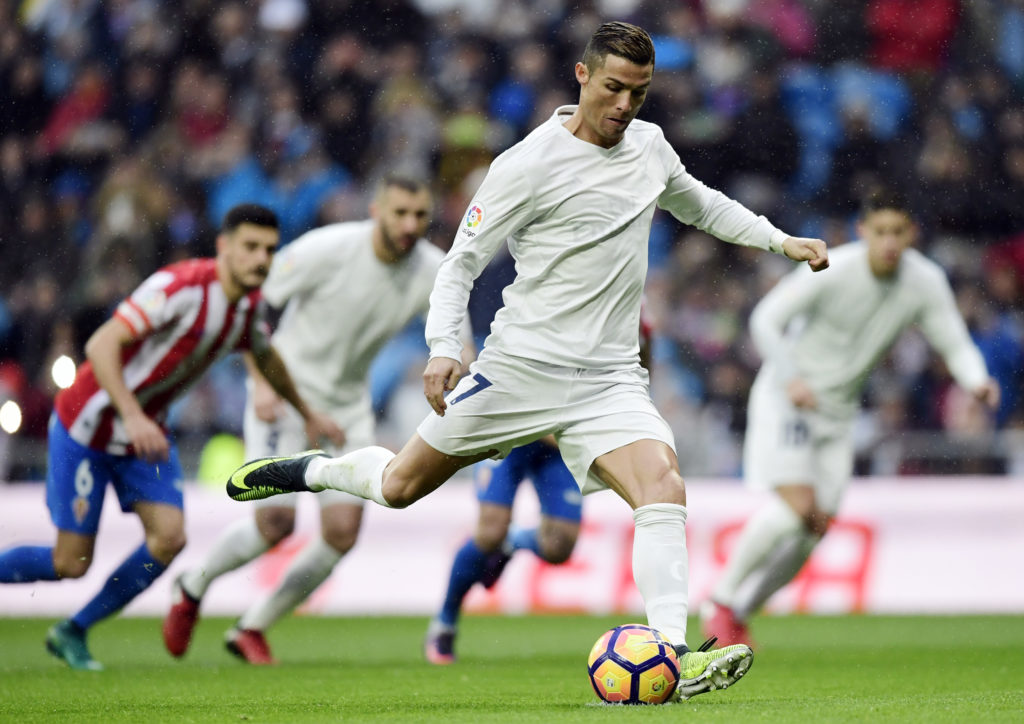 Real Madrid's Portuguese forward Cristiano Ronaldo shoots to score the opening goal during the Spanish league football match Real Madrid CF vs Real Sporting de Gijon at the Santiago Bernabeu stadium in Madrid on November 26, 2016. / AFP PHOTO / JAVIER SORIANO