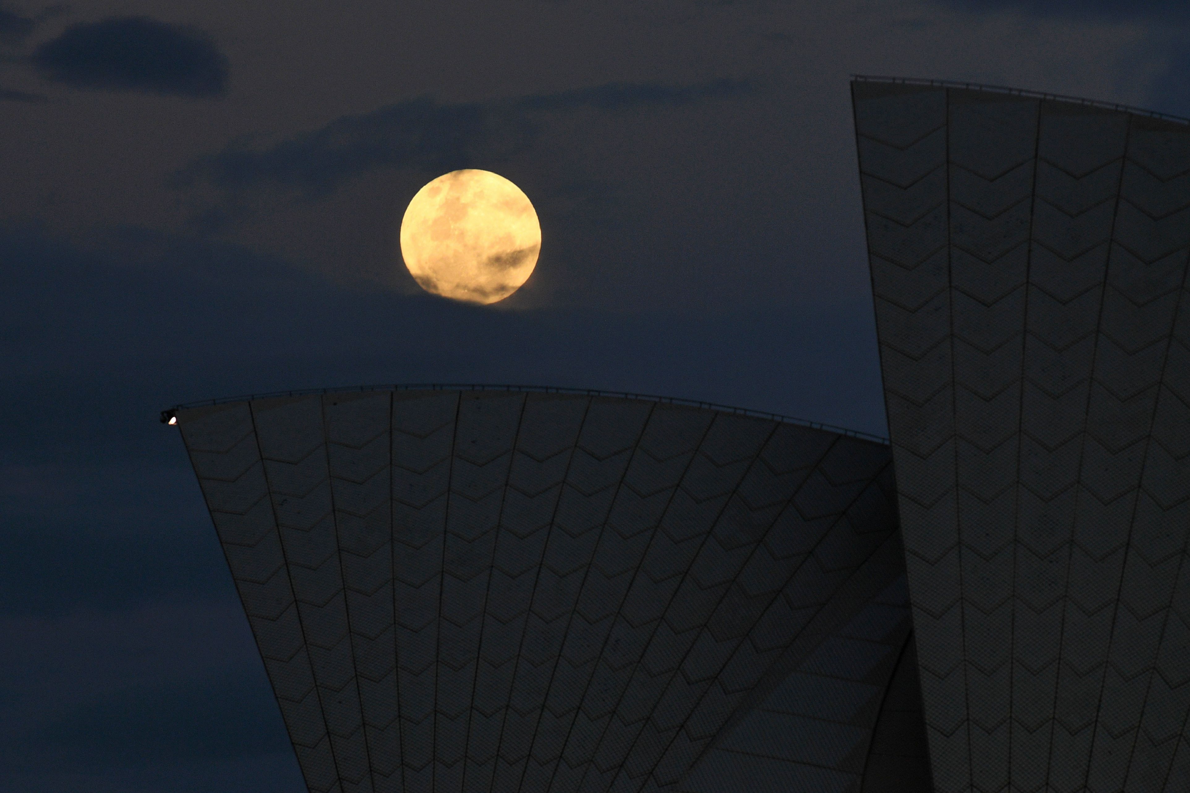 ซุปเปอร์มูนเหนือหลังคาของซิดนีย์โอเปราเฮาส์ ในนครซิดนีย์ ประเทศออสเตรเลีย / AFP PHOTO / WILLIAM WEST