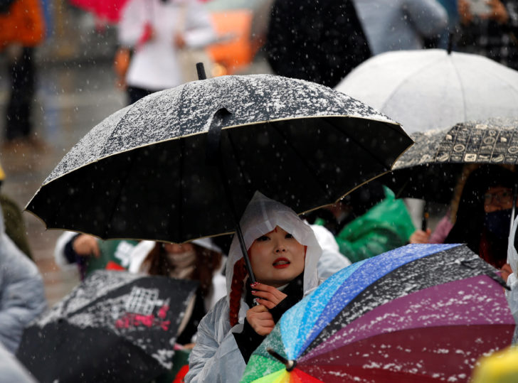 A protester holds an umbrella at a protest calling for South Korean President Park Geun-hye to step down, as it snows in Seoul