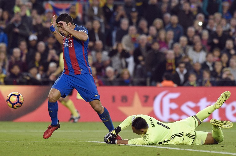 Barcelona's Uruguayan forward Luis Suarez (L) vies with Real Madrid's Costa Rican goalkeeper Keylor Navas prior to scoring a goal during the Spanish league football match FC Barcelona vs Real Madrid CF at the Camp Nou stadium in Barcelona on December 3, 2016. / AFP PHOTO / LLUIS GENE
