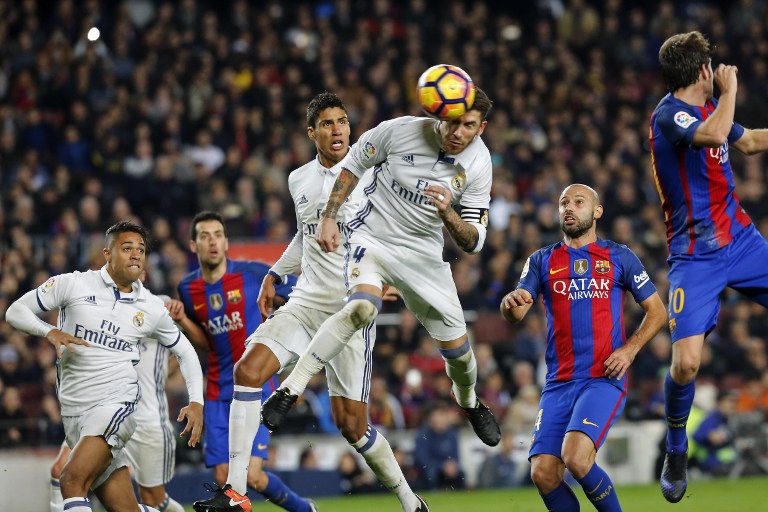 Real Madrid's defender Sergio Ramos (C) heads a ball to score the equalizer past Real Madrid's French defender Raphael Varane (3rdL) and Barcelona's Argentinian defender Javier Mascherano (R) during the Spanish league football match FC Barcelona vs Real Madrid CF at the Camp Nou stadium in Barcelona on December 3, 2016. / AFP PHOTO / PAU BARRENA