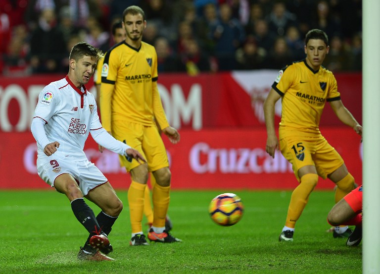 Sevilla's Argentinian forward Luciano Vietto (L) scores a goal during the Spanish league football match Sevilla FC vs Malaga CF at the Ramon Sanchez Pizjuan stadium in Sevilla on December 17, 2016. / AFP PHOTO / CRISTINA QUICLER