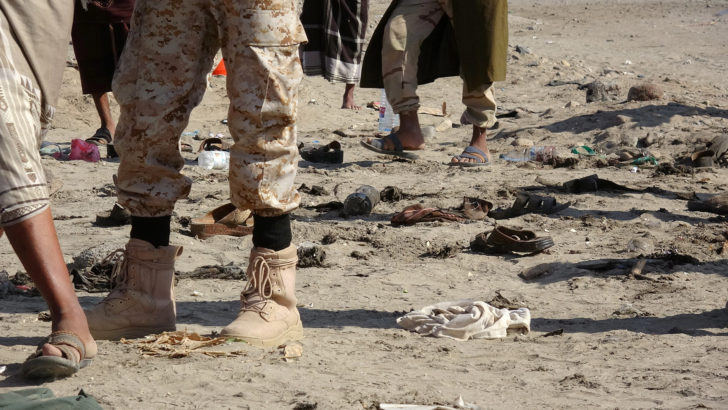 Soldiers stand near shoes of comrades killed by a suicide bombing in the southern port city of Aden, Yemen