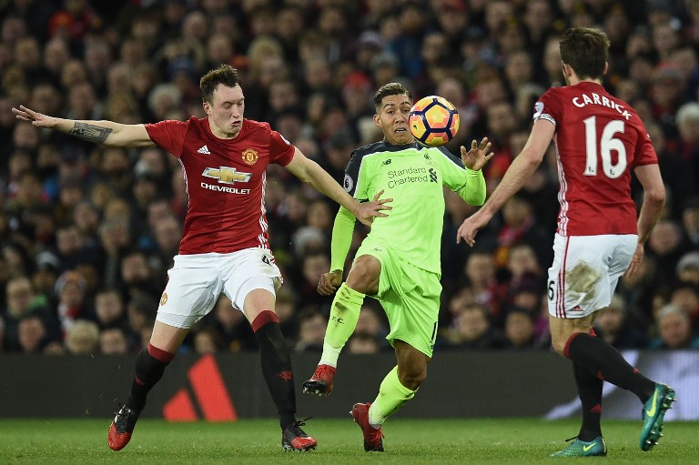 Manchester United's English defender Phil Jones (L) and Manchester United's English midfielder Michael Carrick (R) vie with Liverpool's Brazilian midfielder Roberto Firmino during the English Premier League football match between Manchester United and Liverpool at Old Trafford in Manchester, north west England, on January 15, 2017. / AFP PHOTO / Oli SCARFF / RESTRICTED TO EDITORIAL USE. No use with unauthorized audio, video, data, fixture lists, club/league logos or 'live' services. Online in-match use limited to 75 images, no video emulation. No use in betting, games or single club/league/player publications. /