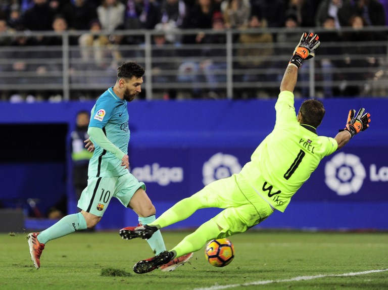 Barcelona's Argentinian forward Lionel Messi (L) shoots to score during the Spanish league football match SD Eibar vs FC Barcelona at the Ipurua stadium in Eibar on January 22, 2017. / AFP PHOTO / ANDER GILLENEA