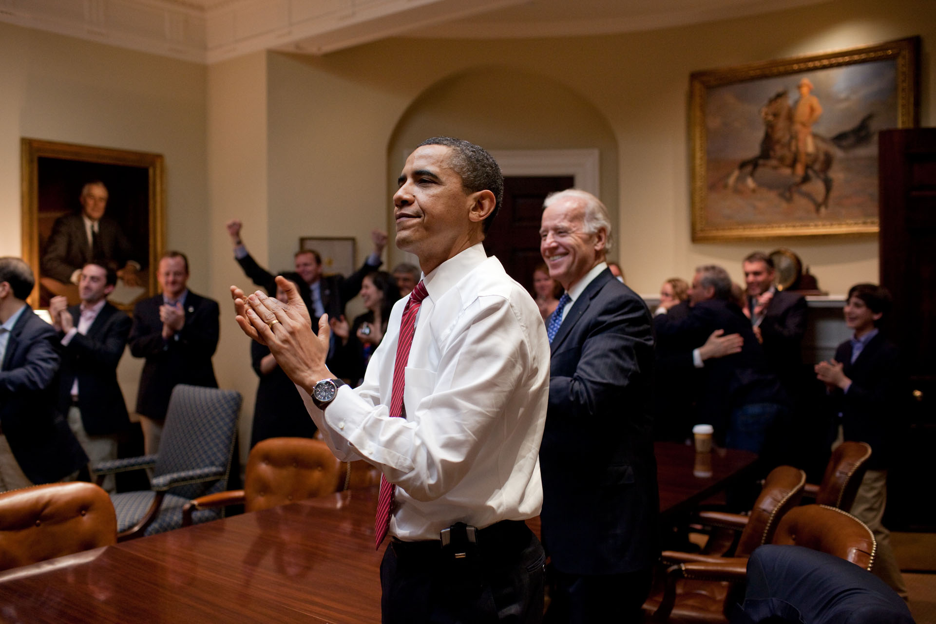 โอบามาและไบเดนปรบมือขณะรับชมสภาผู้แทนราษฎรลงคะแนนผ่านร่างกฎหมายรัฐบัญญัติประกันสุขภาพถ้วนหน้า หรือ ‘โอบามาแคร์’ / Official White House Photo by Pete Souza
