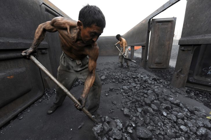 FILE PHOTO: Workers unload coal at a storage site along a railway station in Hefei
