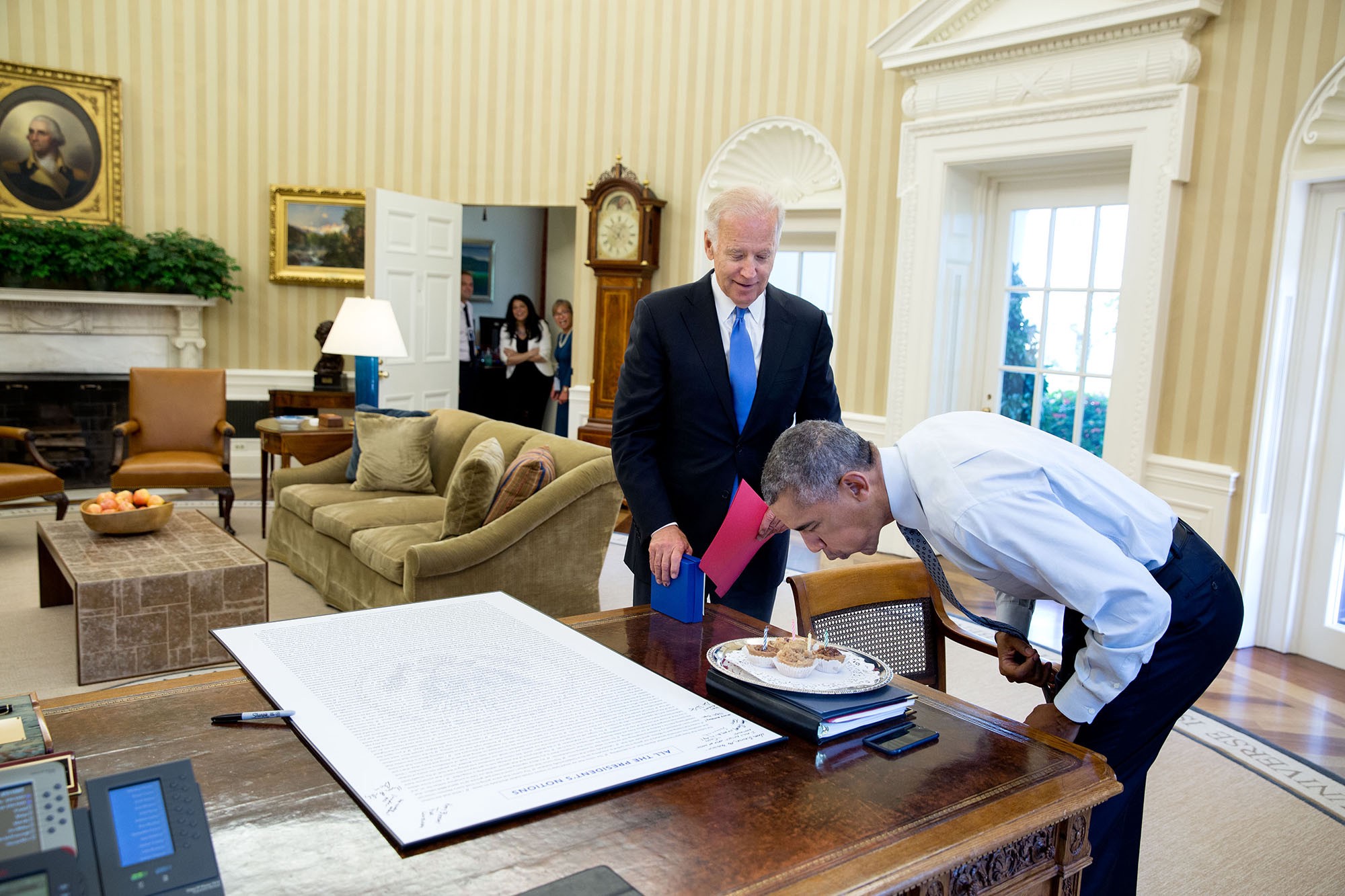 โอบามาเป่าเทียนบนคัพเค้กฉลองวันเกิดที่ไบเดนและเจ้าหน้าที่ทำเนียบขาวนำมามอบให้เป็นการเซอร์ไพรส์ เมื่อ 4 สิงหาคม 2559 / Official White House Photo by Pete Souza