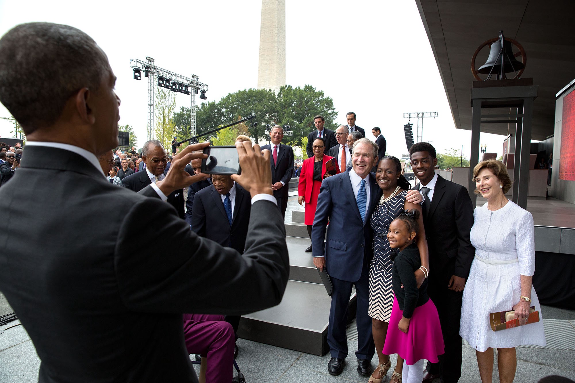  โอบามาถ่ายภาพให้อดีตประธานาธิบดีจอร์จ ดับเบิลยู. บุช และลอรา บุช ภริยา ระหว่างร่วมพิธีเปิดพิพิธภัณฑ์แอฟริกันอเมริกัน เมื่อ 24 กันยายน 2559 / Official White House Photo by Pete Souza