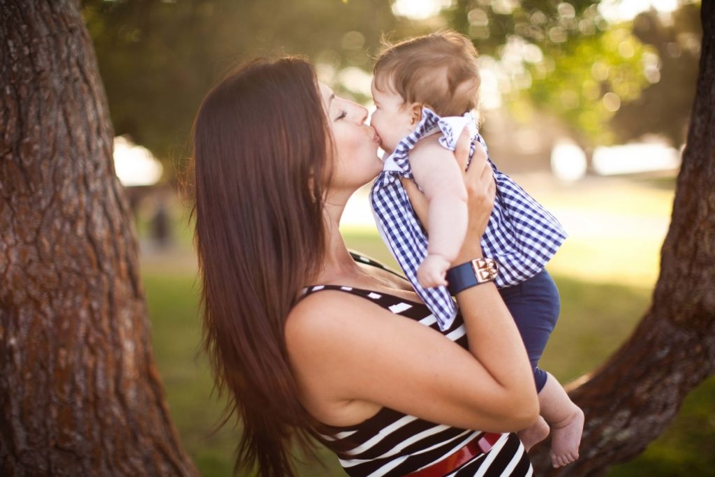 Portrait of mother kissing baby daughter