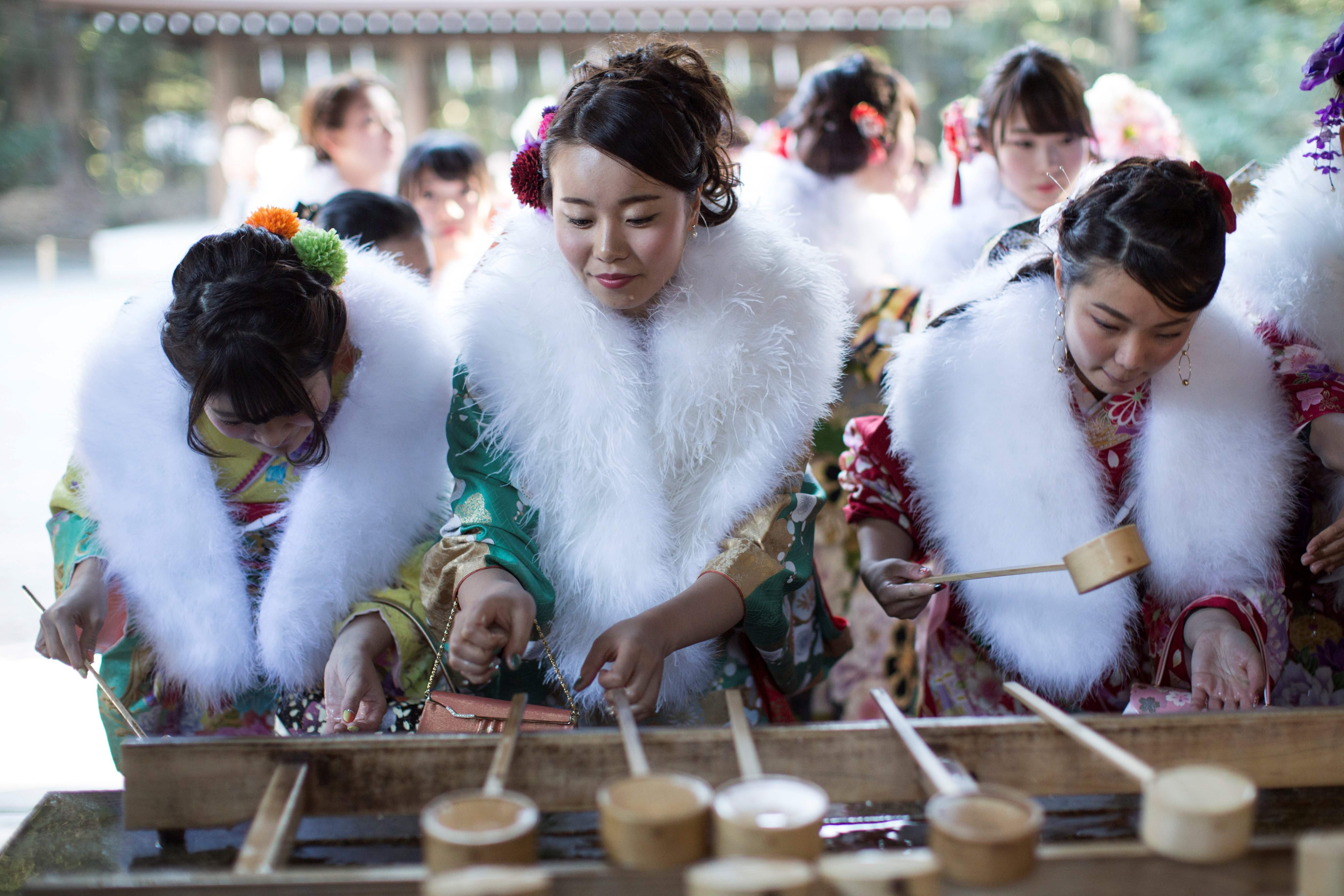 In this photo taken on January 6, 2017, twenty-year-old Japanese female tour guides, dressed in traditional kimonos, wash their hands during a purification ceremony to celebrate their Coming-of-Age at Meiji shrine in Tokyo. / AFP PHOTO / Behrouz MEHRI