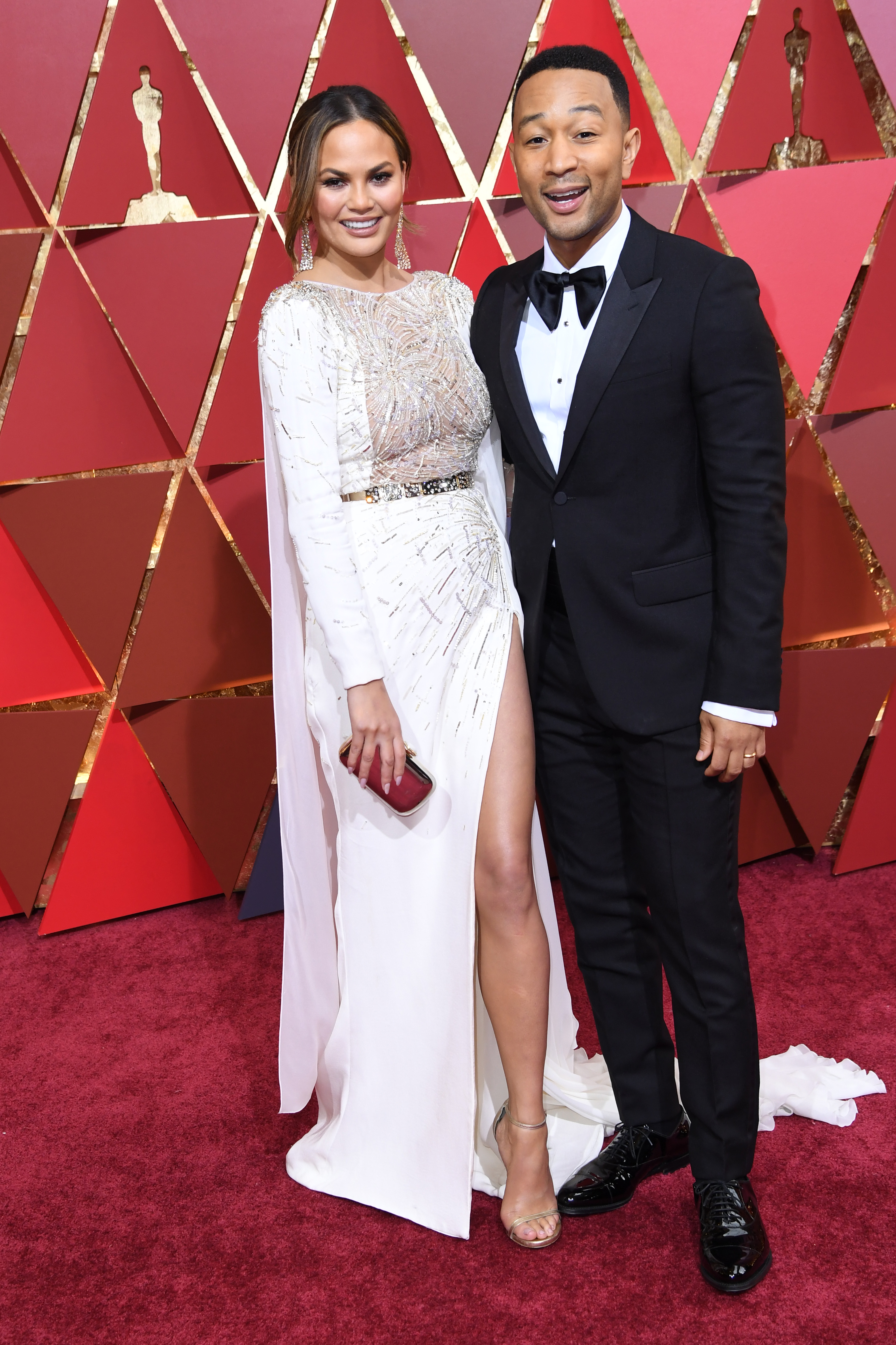 US singer John Legend (R) and his wife US model Chrissy Teigen pose as they arrive on the red carpet for the 89th Oscars on February 26, 2017 in Hollywood, California.  / AFP PHOTO / ANGELA WEISS