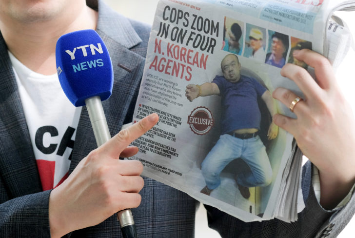 A reporter holds up a local newspaper during his report in front of the morgue at Kuala Lumpur General Hospital where Kim Jong Nam's body is held for autopsy in Malaysia