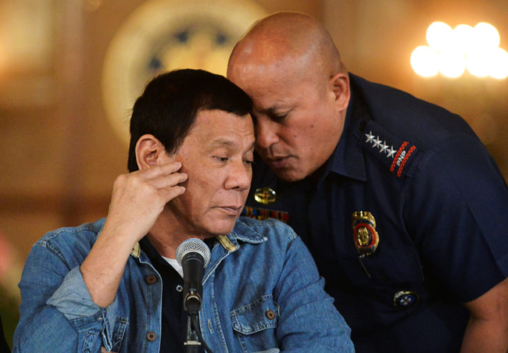 Philippine National Police chief General Ronald Dela Rosa whispers to President Rodrigo Duterte during the announcement of the disbandment of police operations against illegal drugs at the Malacanang palace in Manila