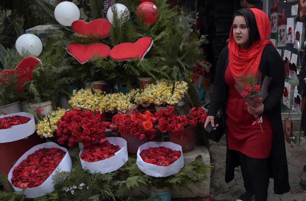 An Afghan woman carries roses as she leaves a flower shop on Valentine's Day in Kabul on February 14, 2017. In conservative Afghanistan, many Afghans are unaware of or don't mark Valentine's Day, but younger generations in urban areas are celebrating the day despite restrictions. / AFP PHOTO / SHAH MARAI