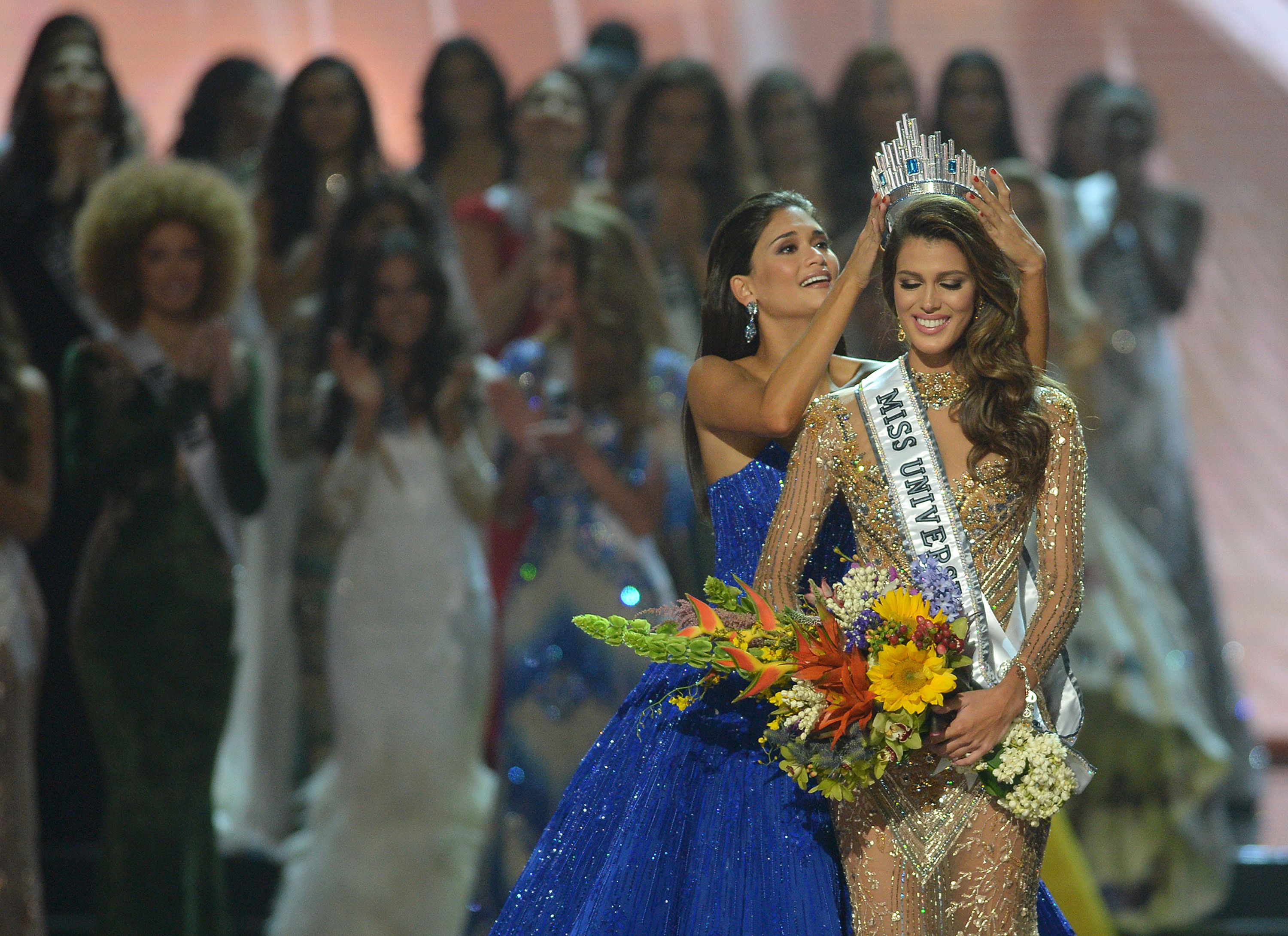 Miss Universe contestant Iris Mittenaere (R) of France is crowned the new 2017 winner by former Miss Universe Pia Wurtzbach of the Philippines (C) during the Miss Universe pageant at the Mall of Asia Arena in Manila on January 30, 2017. France was crowed Miss Universe on January 30 in a glitzy spectacle free of last year's dramatic mix-up but with a dash of political controversy as finalists touched on migration and other hot-button global issues. / AFP PHOTO / TED ALJIBE