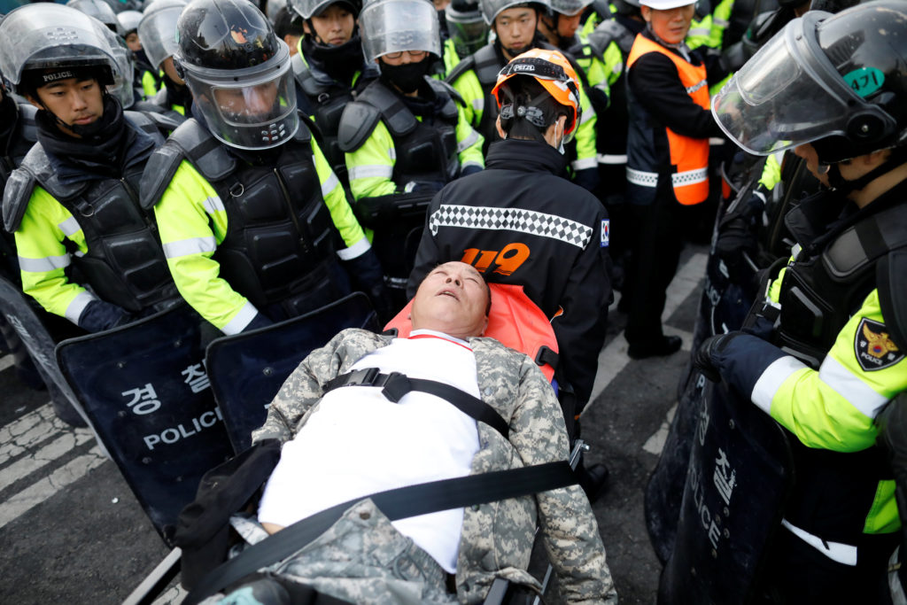 ผู้สนับสนุนประธานาธิบดีปาร์ค กึน-เฮ ที่ได้รับบาดเจ็บ ถูกนำขึ้นเปลหามส่งโรงพบาบาล (ภาพรอยเตอร์)