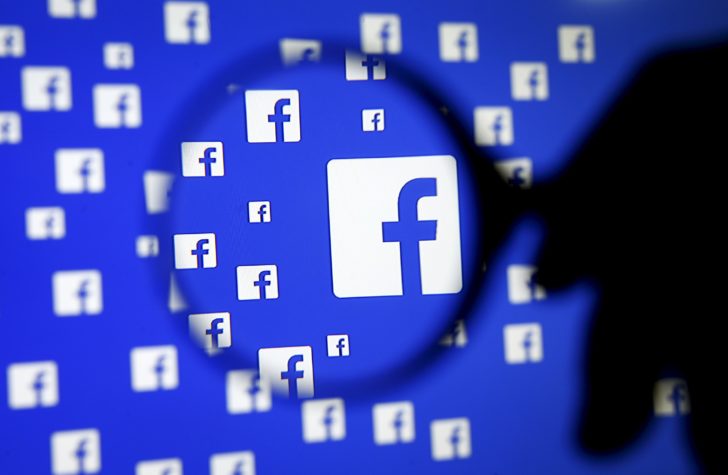A man poses with a magnifier in front of a Facebook logo on display in this illustration taken in Sarajevoin this file photo