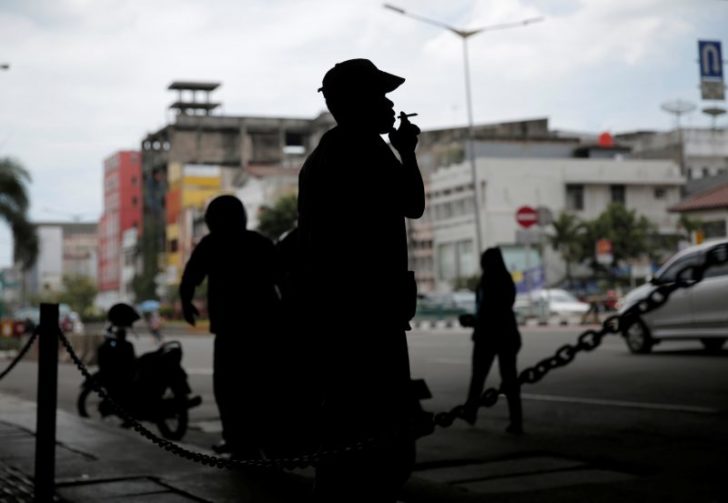 A man smokes a cigarette on a street in Jakarta