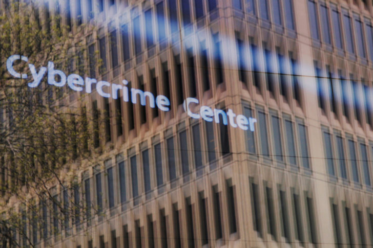 An advertisement about the Microsoft Cybercrime Center plays behind a window reflecting a nearby building at the Microsoft office in Cambridge