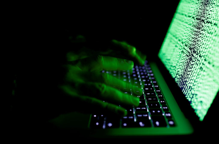 FILE PHOTO: Man types on a computer keyboard in front of the displayed cyber code in this illustration picture