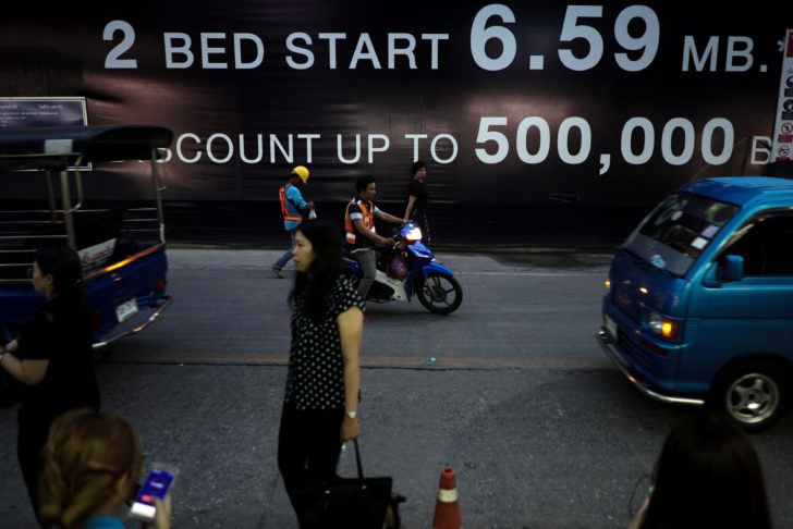 People walk past an advertising board of a condominium in Bangkok