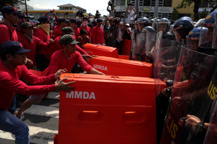 Protesters push barricade towards anti-riot police officers during a protest to denounce the visit of U.S. President Donald Trump, who will attend the 31st Association of Southeast Asian Nations (ASEAN) leaders summit, in metro Manila