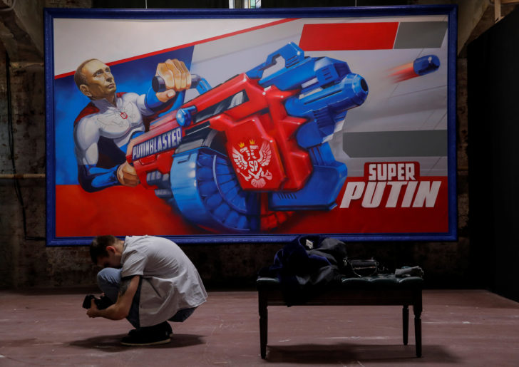 A photographer takes pictures in front of a painting depicting Russian president Vladimir Putin at the