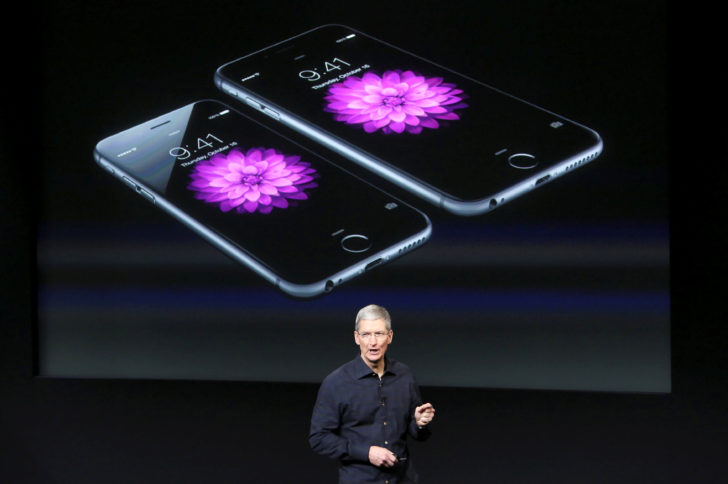 FILE PHOTO: Apple CEO Tim Cook stands in front of a screen displaying the IPhone 6 during a presentation at Apple headquarters in Cupertino