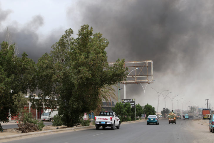 Smoke billows from a car parts store hit by shells during the conflict in the port city of Aden
