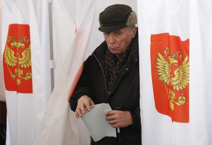 A man walks out of a voting booth at a polling station during the presidential election in Moscow