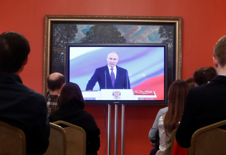 Journalists watch a ceremony to inaugurate Vladimir Putin as President of Russia at a press centre in Moscow